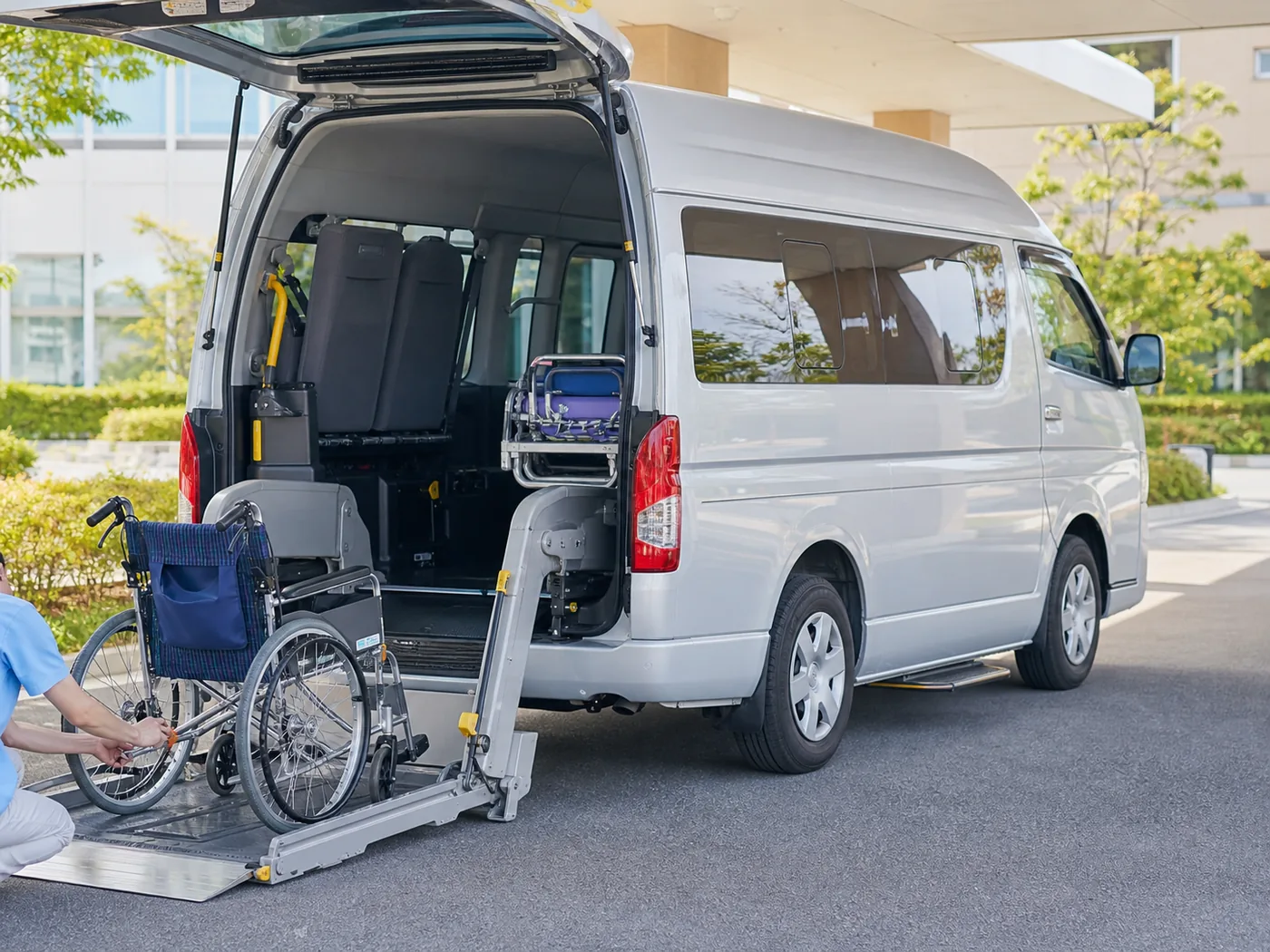 ハイエースの後部リフトで車いすを載せる準備をするスタッフ